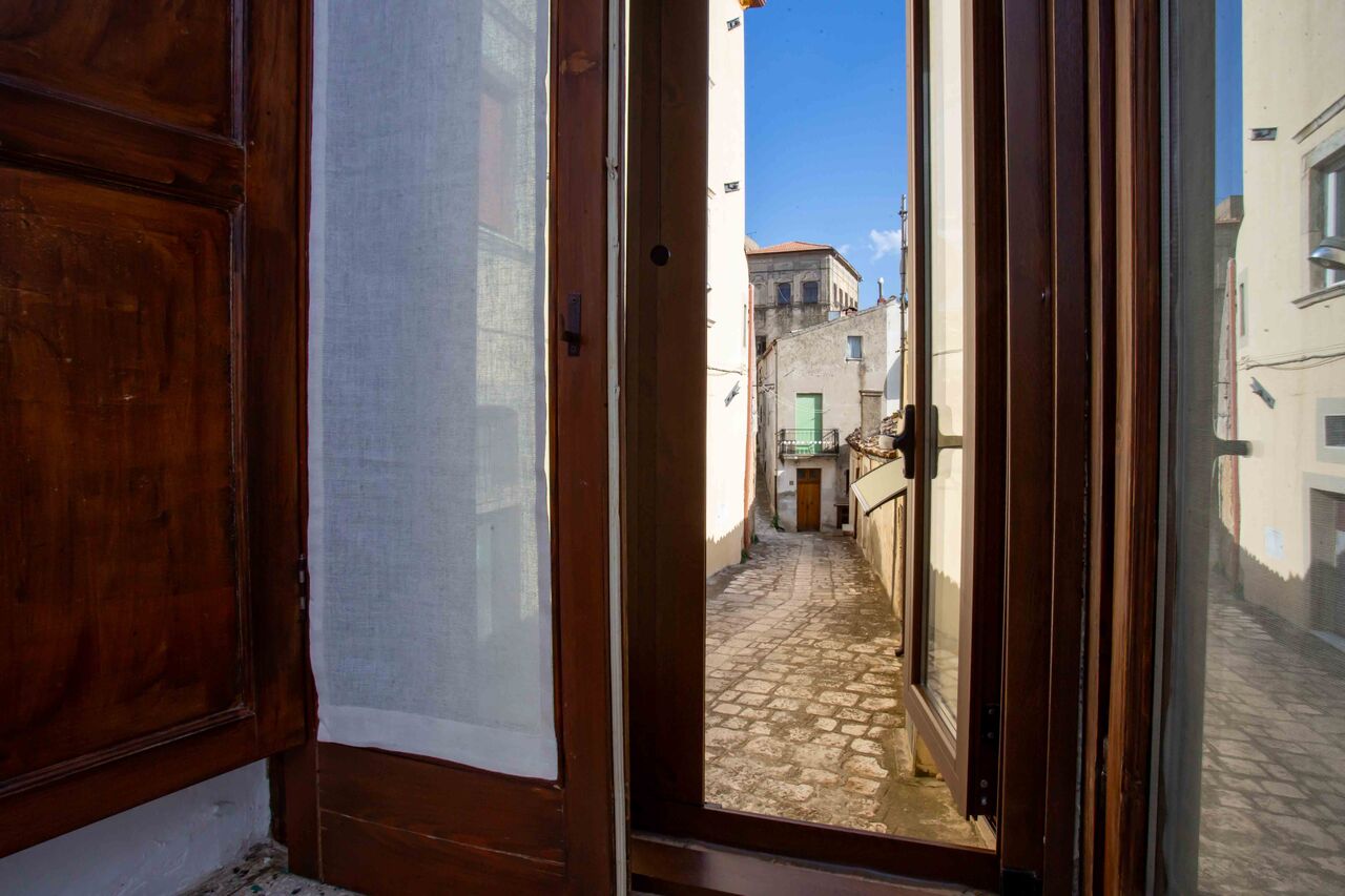 La porta-finestra aperta di Domus Rosae sul vicolo in pietra di Tricarico